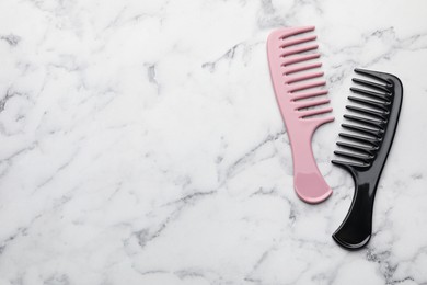 Photo of Different plastic hair combs on white marble table, top view. Space for text