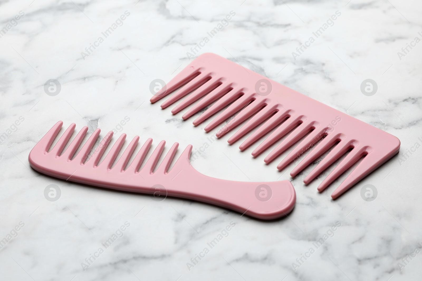 Photo of Different pink plastic combs on white marble table, closeup