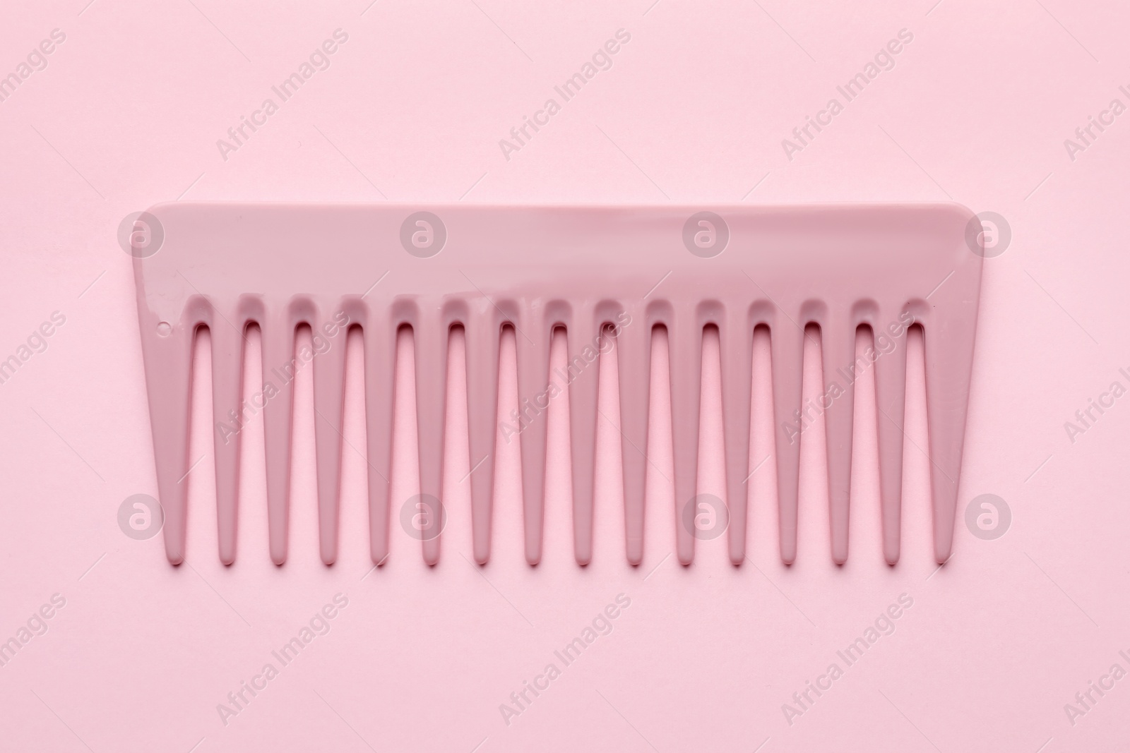 Photo of One plastic hair comb on pink background, top view