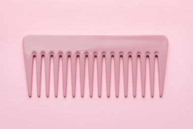 Photo of One plastic hair comb on pink background, top view