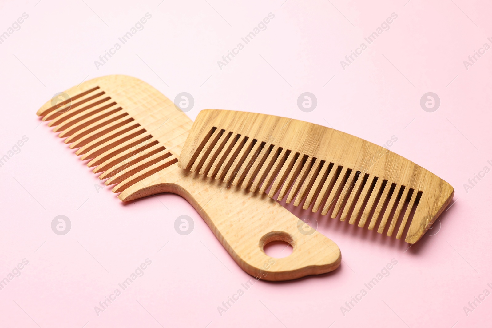 Photo of Different wooden hair combs on pink background, closeup