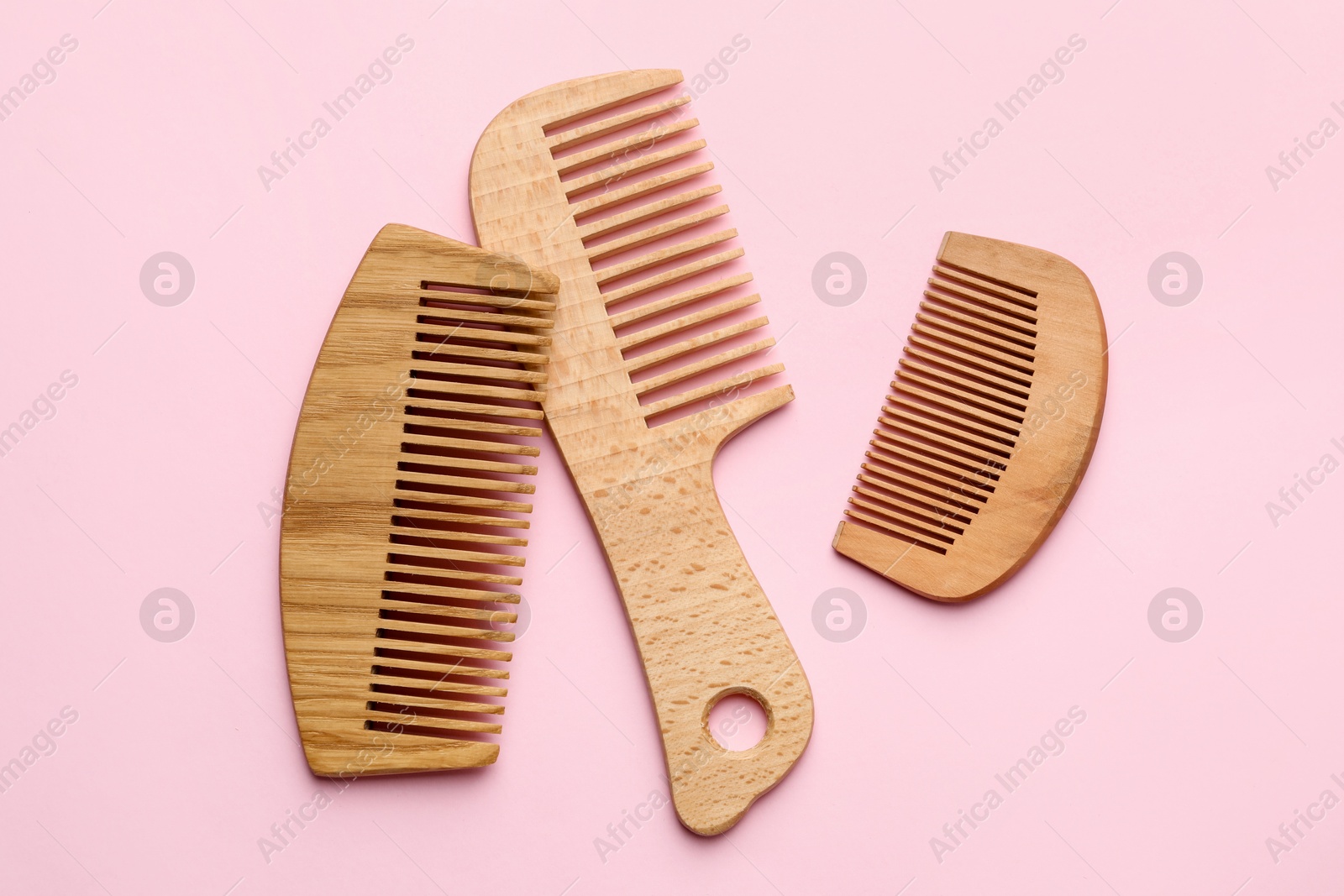 Photo of Different wooden hair combs on pink background, top view