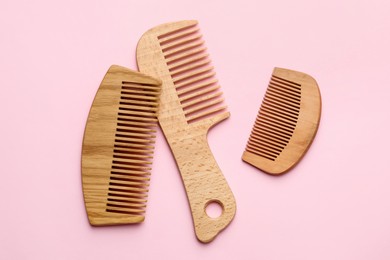 Photo of Different wooden hair combs on pink background, top view