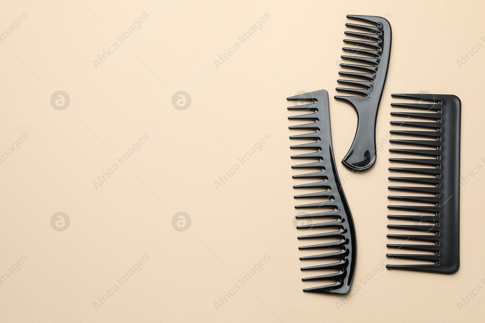 Photo of Different black plastic combs on beige background, top view. Space for text