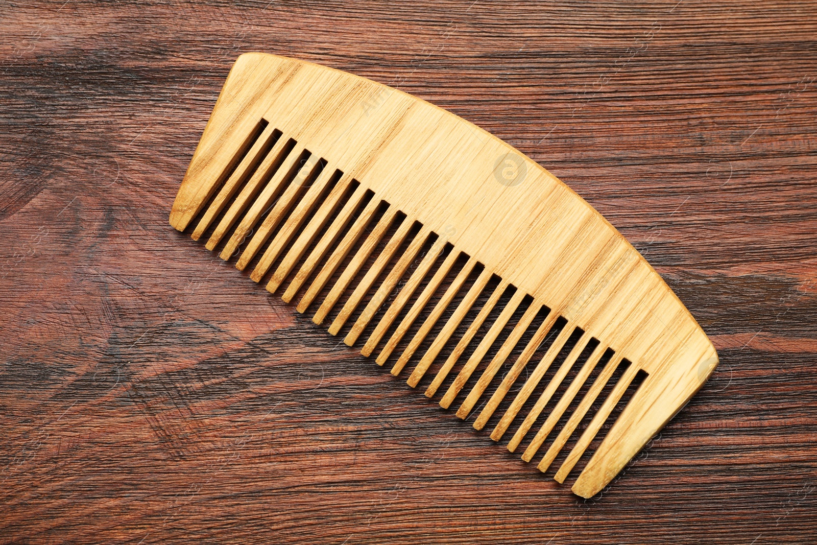 Photo of One hair comb on wooden background, top view