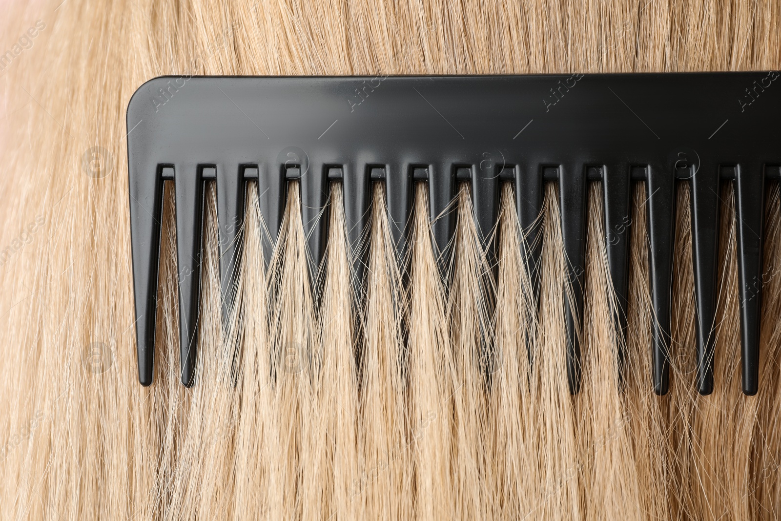 Photo of Brushing hair with plastic comb, closeup view