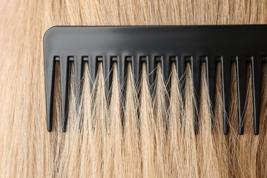 Photo of Brushing hair with plastic comb, closeup view