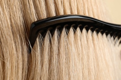 Photo of Brushing hair with plastic comb, closeup view