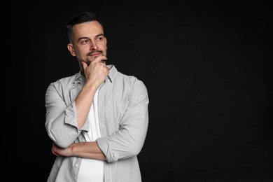 Portrait of handsome middle aged man on black background, space for text