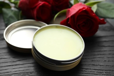 Photo of Natural solid perfume and roses on black wooden table, closeup