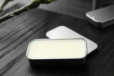 Photo of Natural solid perfume and branch on black wooden table, closeup