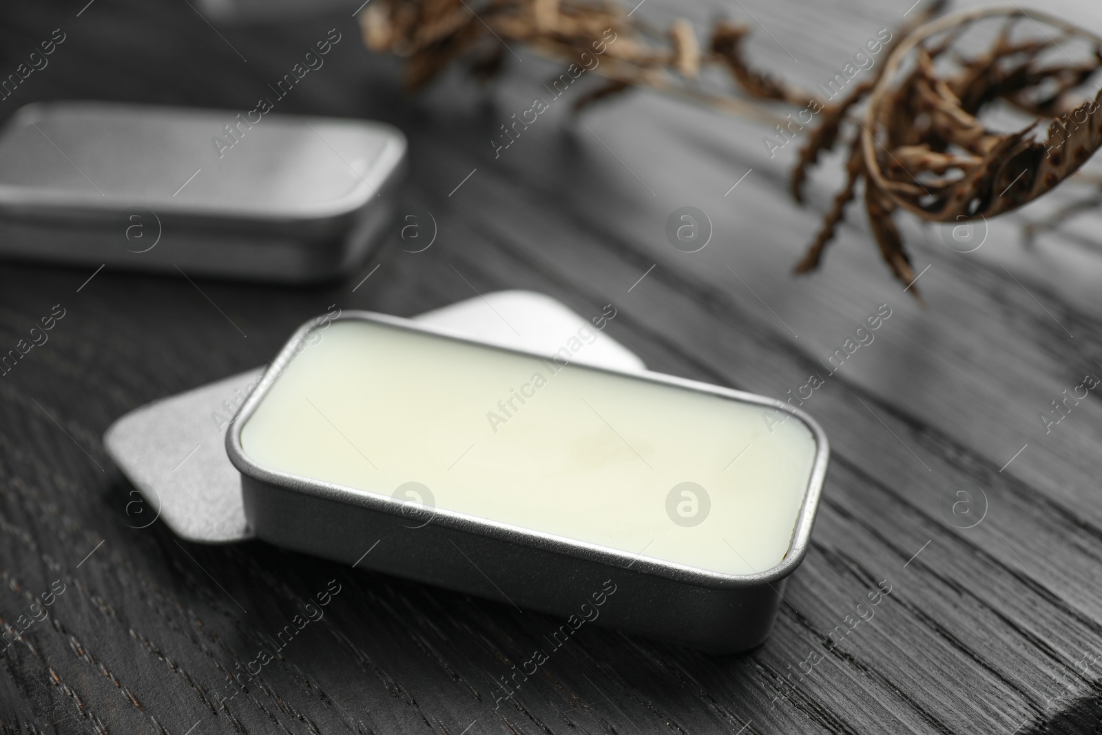 Photo of Natural solid perfume and dry branch on black wooden table, closeup