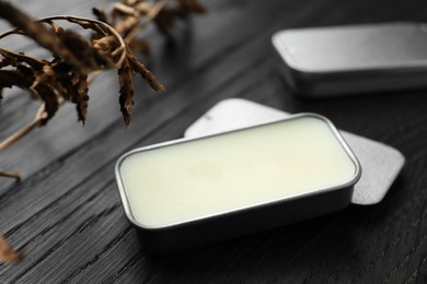 Photo of Natural solid perfume and dry branch on black wooden table, closeup