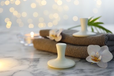 Photo of Spa stones, orchid flowers, towels and leaf on white marble table, closeup. Space for text