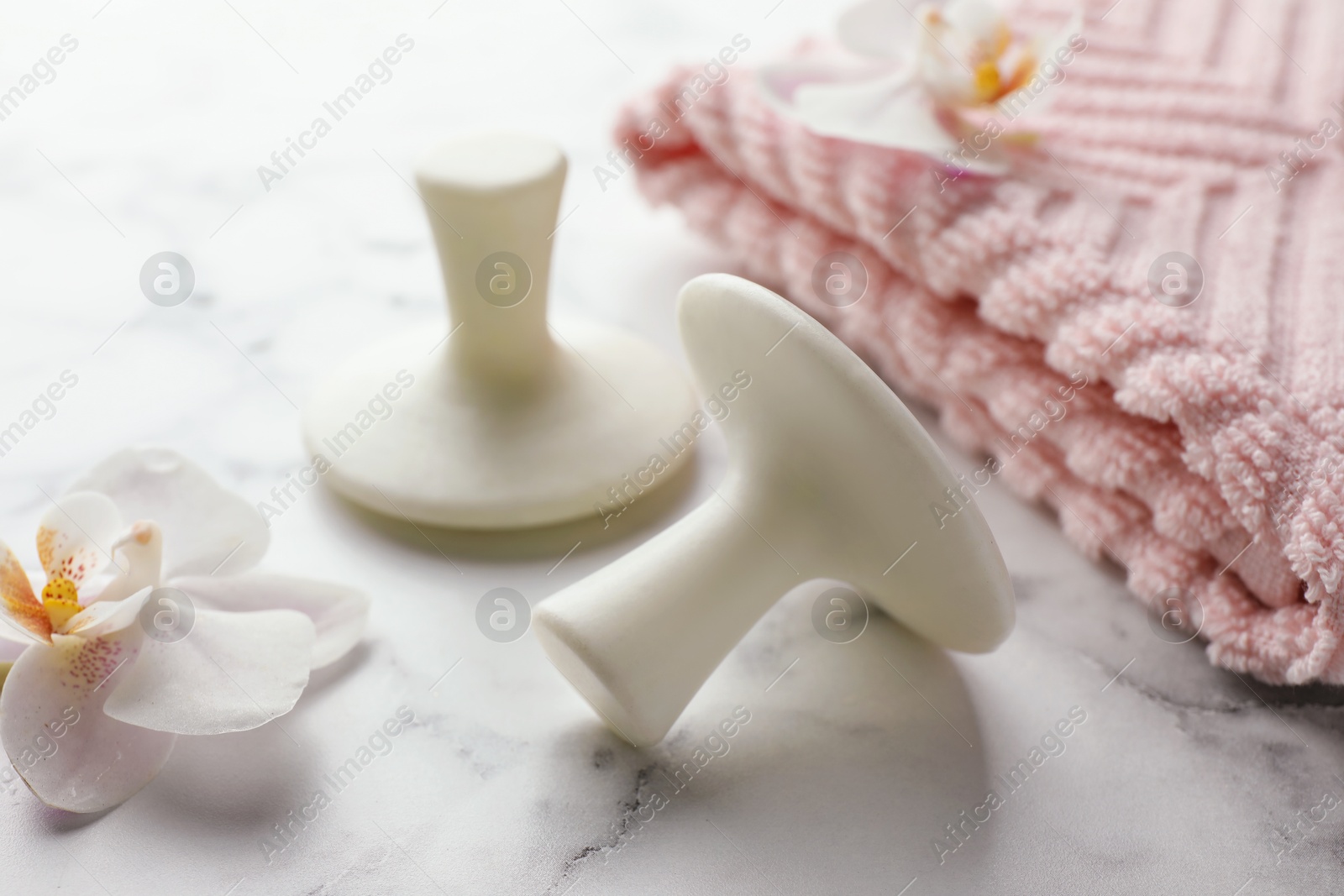 Photo of Wet spa stones, orchid flowers and towel on white marble table, closeup