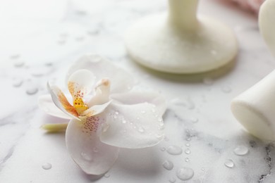 Photo of Orchid flower and spa stones on white marble table, closeup