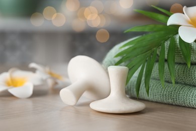 Photo of Spa stones, towel, plumeria flowers and green leaf on wooden table, closeup