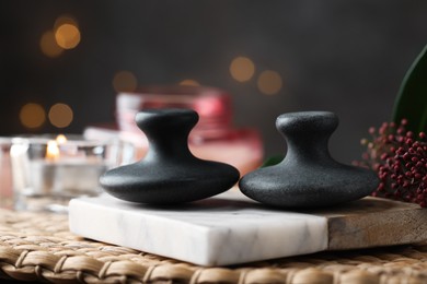 Photo of Spa stones, floral decor and candle on wicker mat, closeup