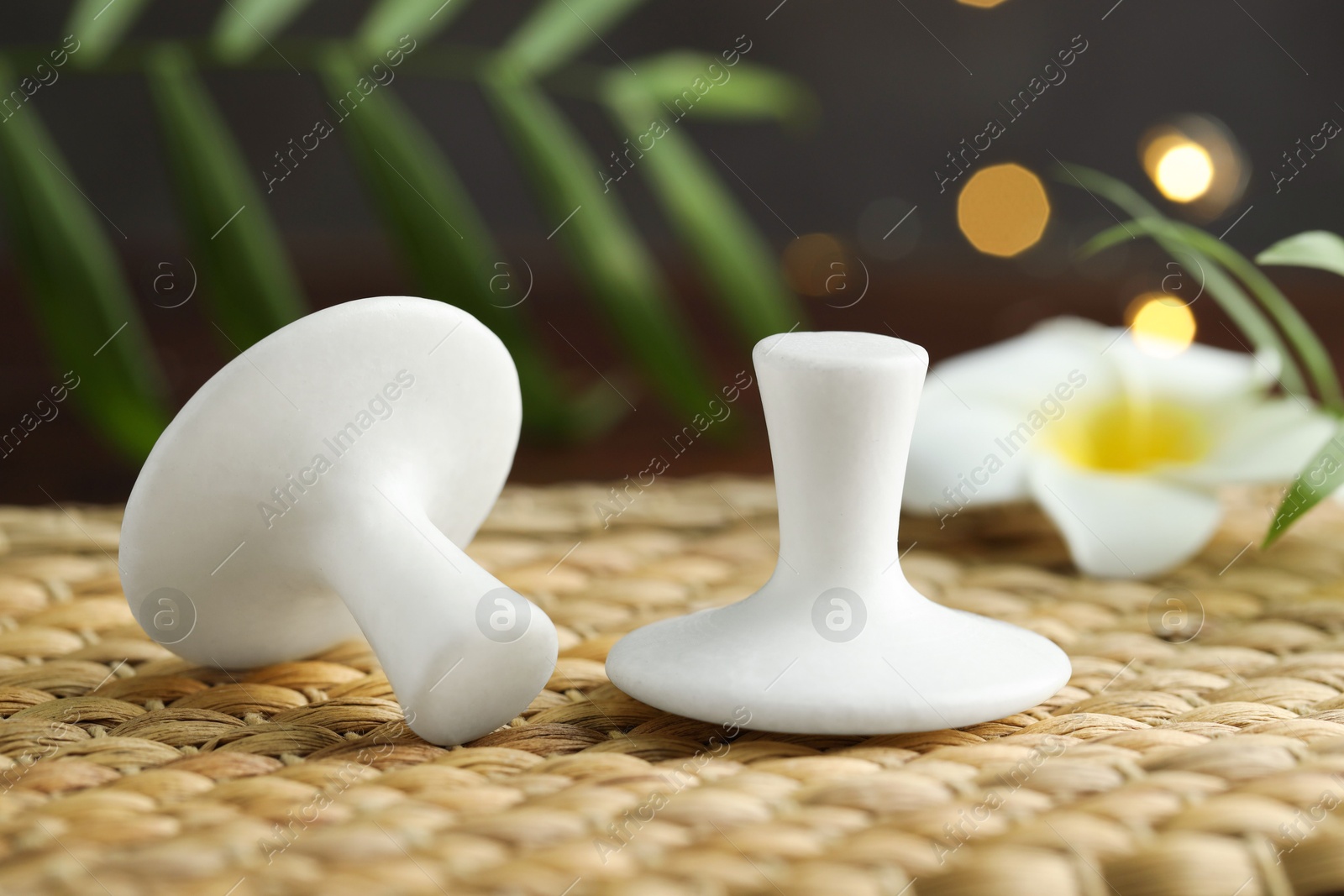 Photo of Spa stones and plumeria flower on wicker mat, closeup