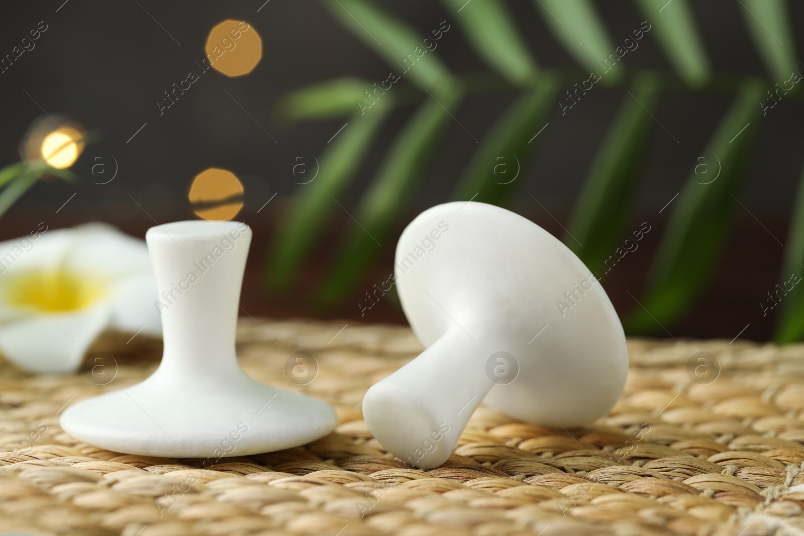 Photo of Spa stones and plumeria flower on wicker mat, closeup