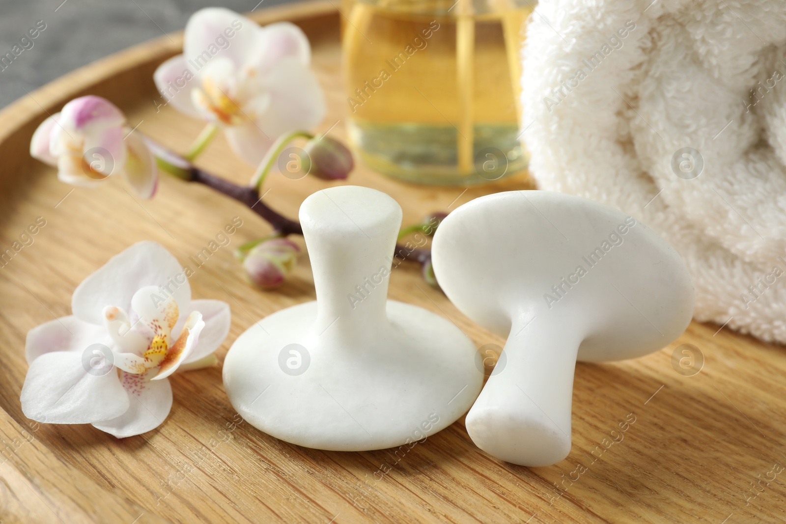 Photo of Spa stones, orchid flowers and towel on wooden tray, closeup