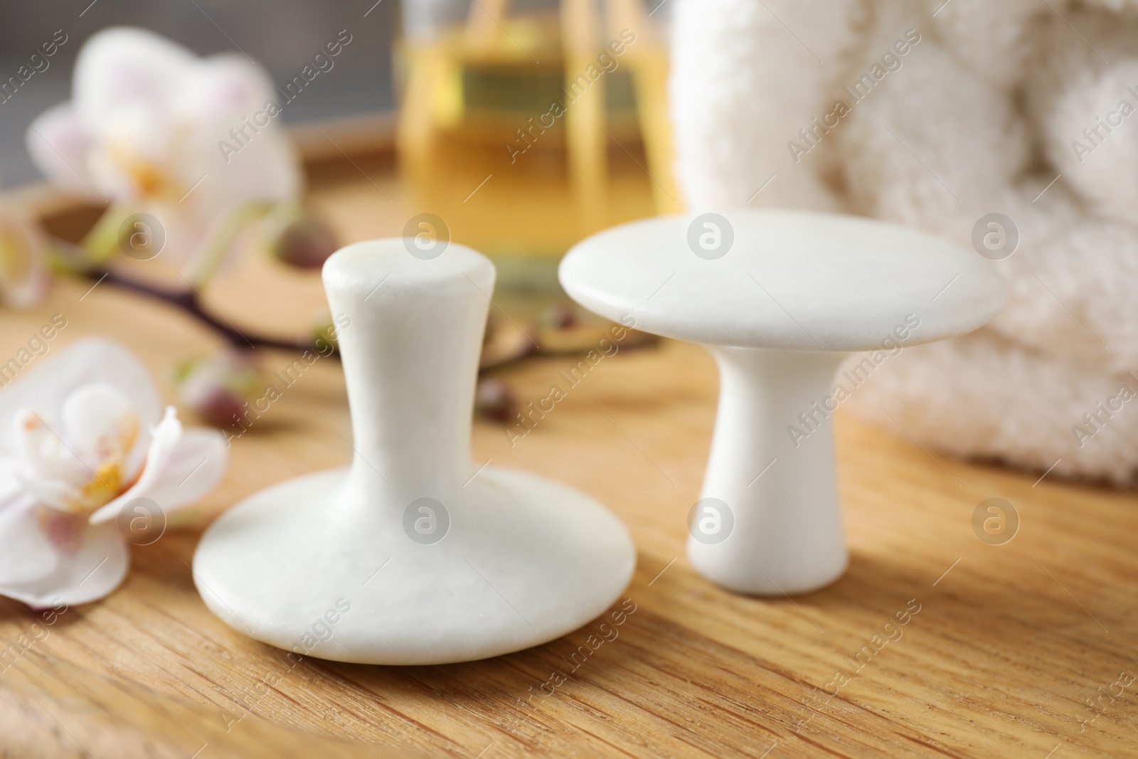 Photo of Spa stones, orchid flowers and towel on wooden tray, closeup