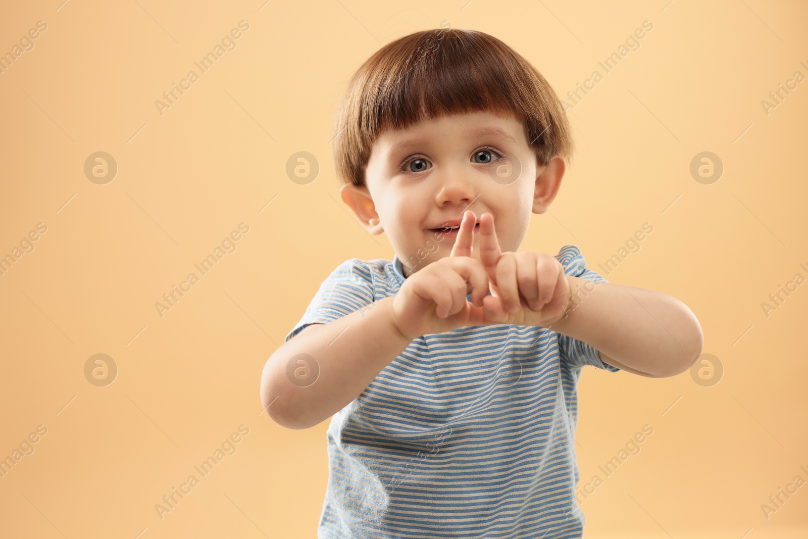 Photo of Portrait of cute little boy gesturing on beige background. Space for text