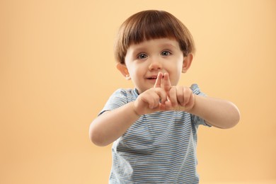 Photo of Portrait of cute little boy gesturing on beige background. Space for text