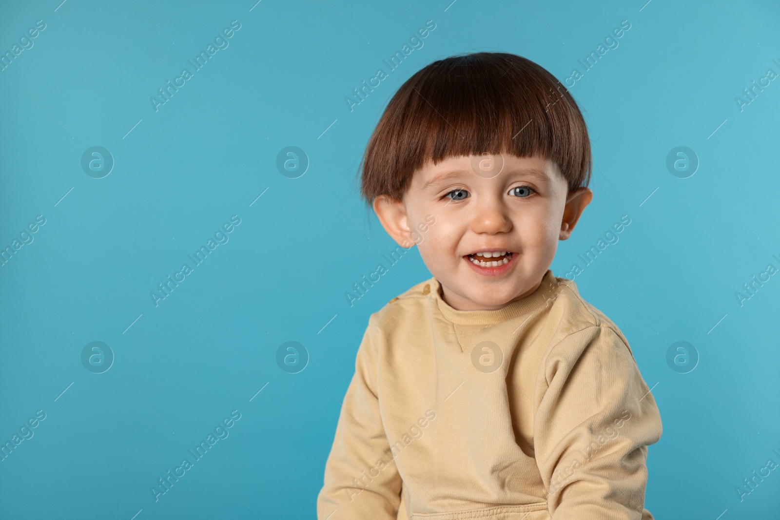 Photo of Portrait of happy little boy on light blue background. Space for text