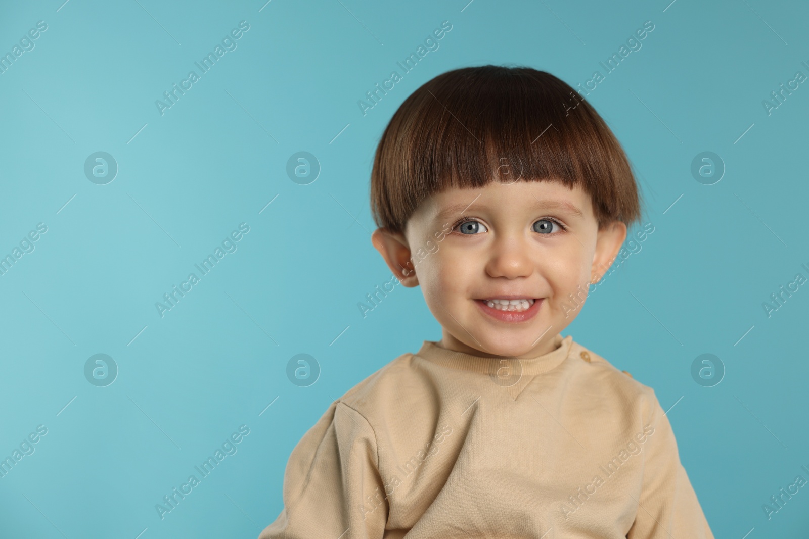 Photo of Portrait of happy little boy on light blue background. Space for text