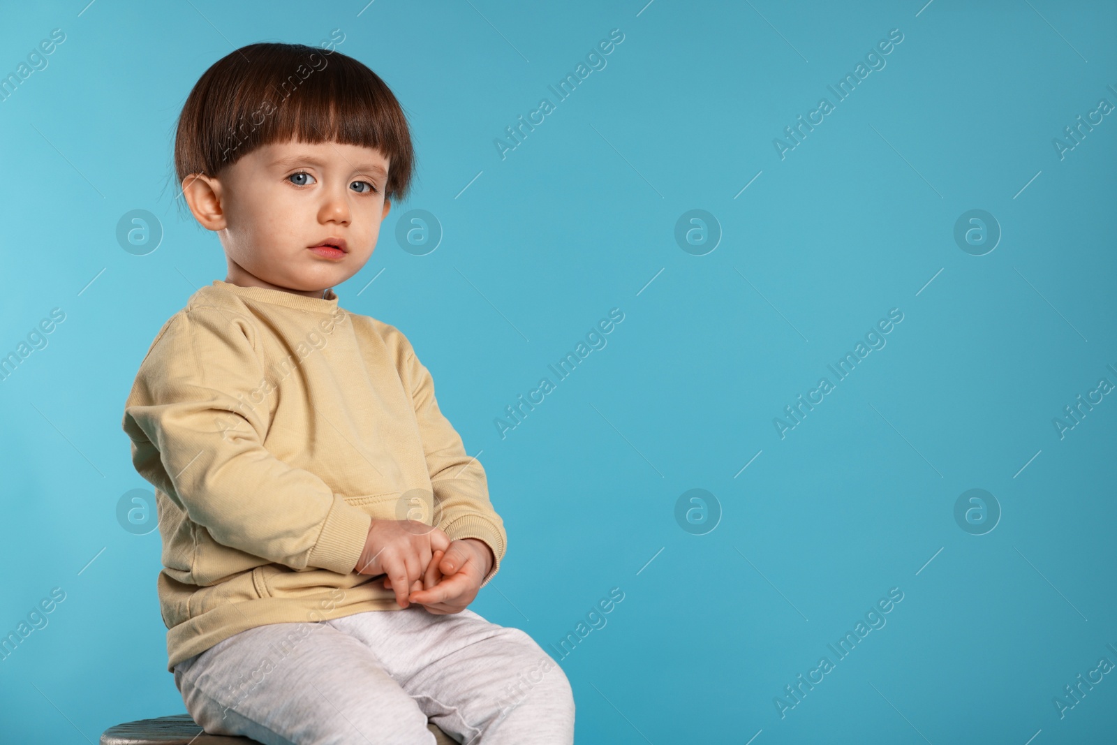 Photo of Portrait of cute little boy on light blue background. Space for text