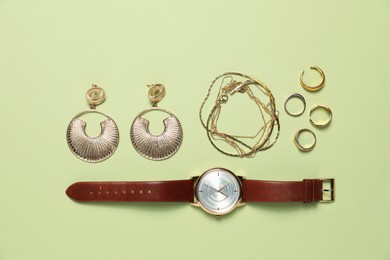 Photo of Flat lay composition with golden jewelry and watch on light green background