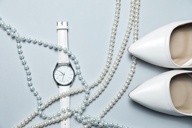 Photo of Stylish pearl necklaces, watch and shoes on light grey background, flat lay