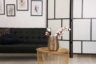 Photo of Cotton flowers on stylish coffee table in room