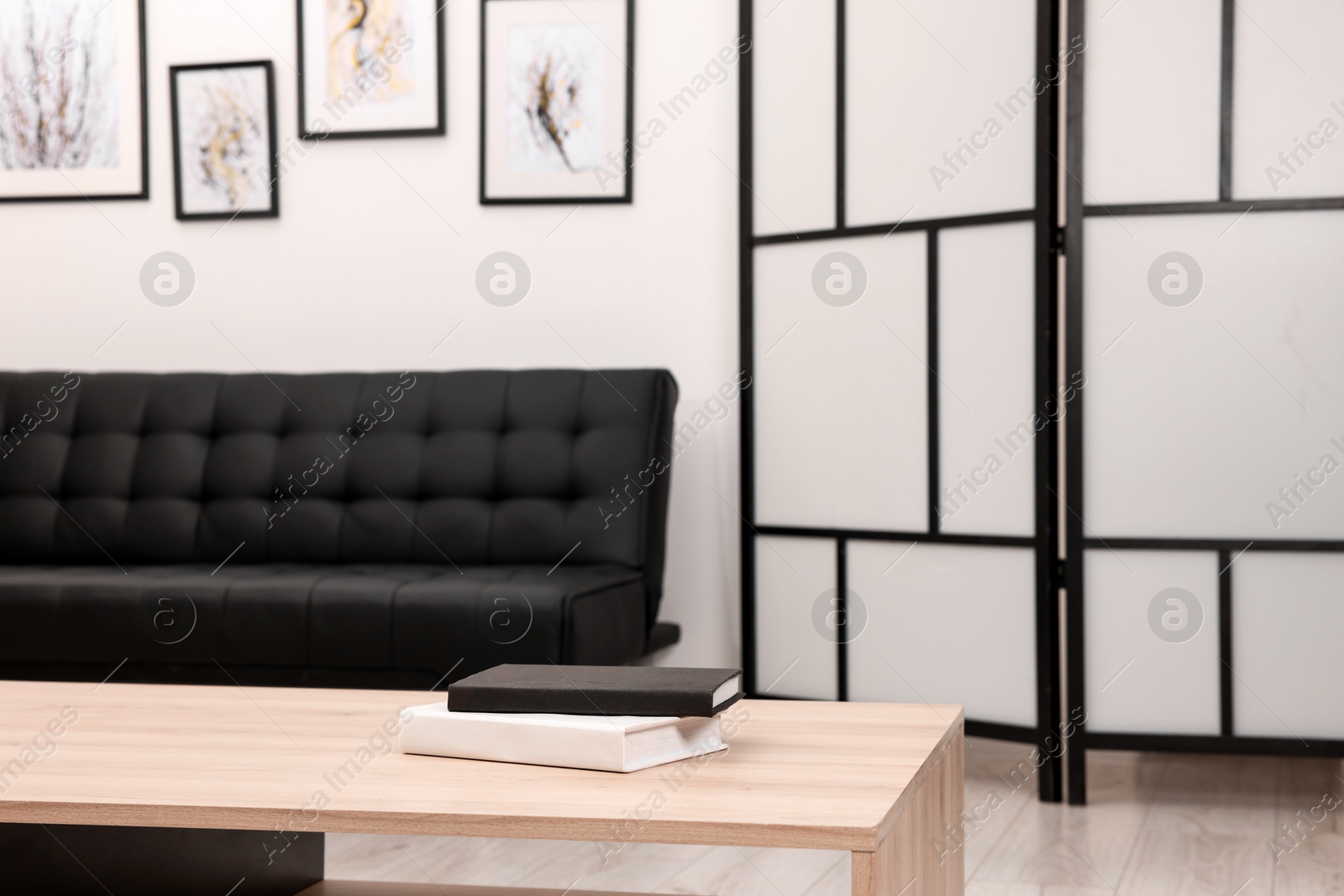 Photo of Books on stylish coffee table near black sofa in room