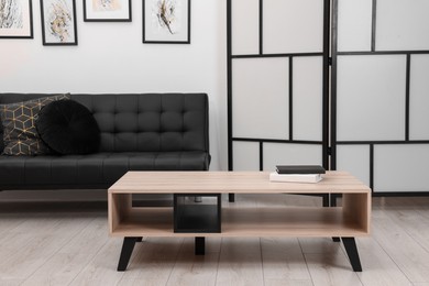 Photo of Books on stylish coffee table near black sofa in room