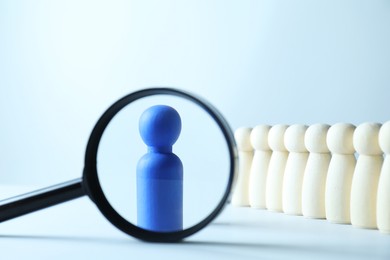 Photo of Human resources concept. Looking at blue figure through magnifying glass on light background, closeup