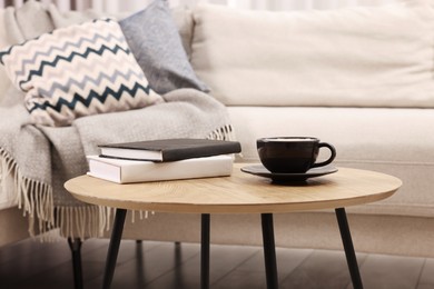 Photo of Cup of drink and books on wooden coffee table near sofa in room