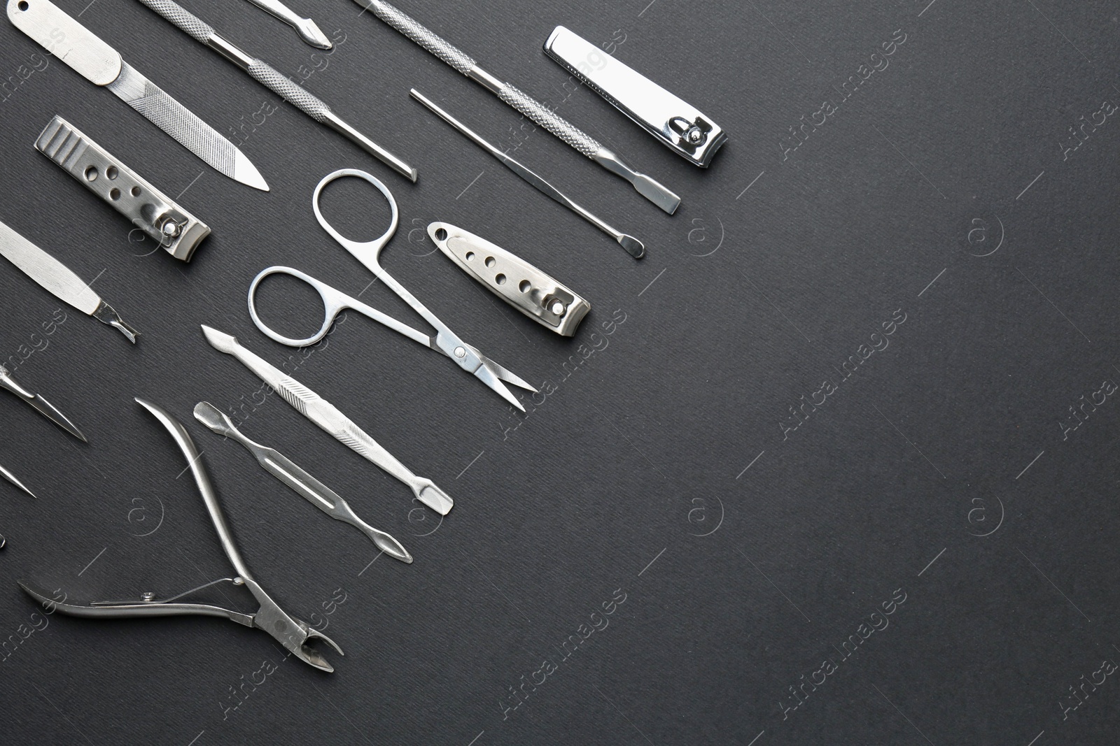 Photo of Set of pedicure tools on black background, flat lay. Space for text