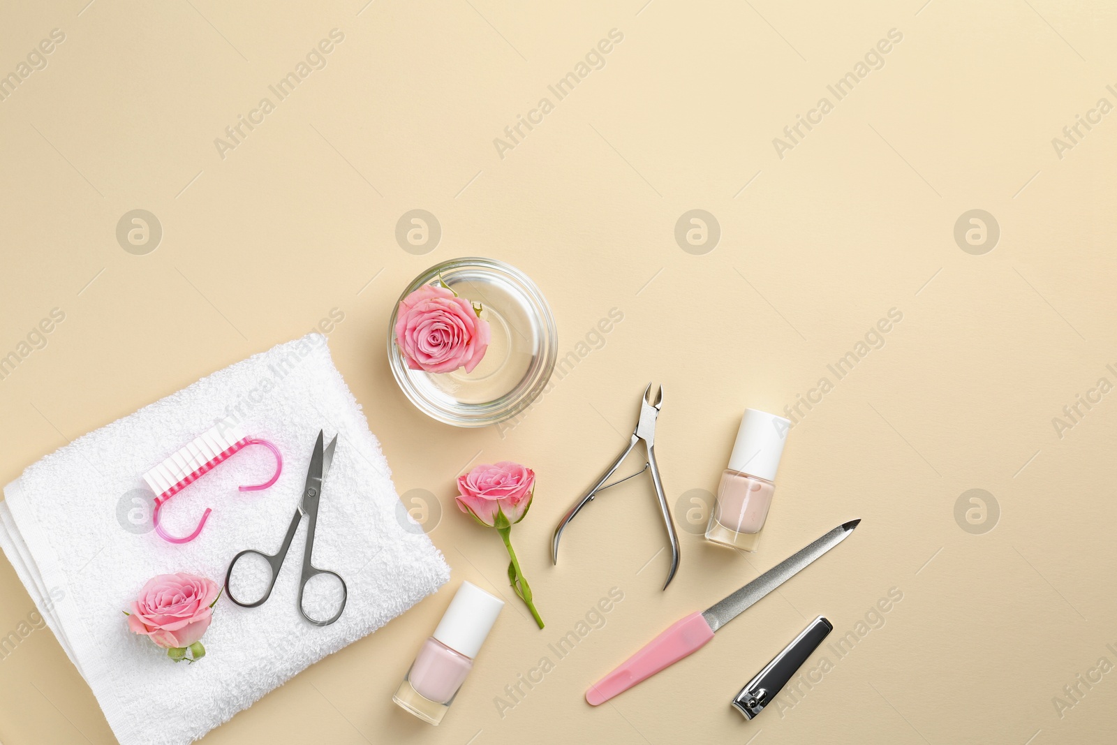 Photo of Set of pedicure tools and flowers on beige background, flat lay. Space for text