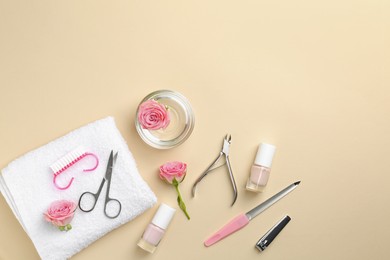 Photo of Set of pedicure tools and flowers on beige background, flat lay. Space for text