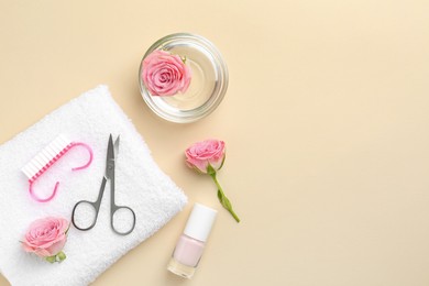 Photo of Set of pedicure tools and flowers on beige background, flat lay. Space for text