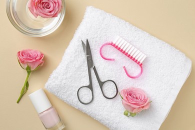 Photo of Set of pedicure tools and flowers on beige background, flat lay