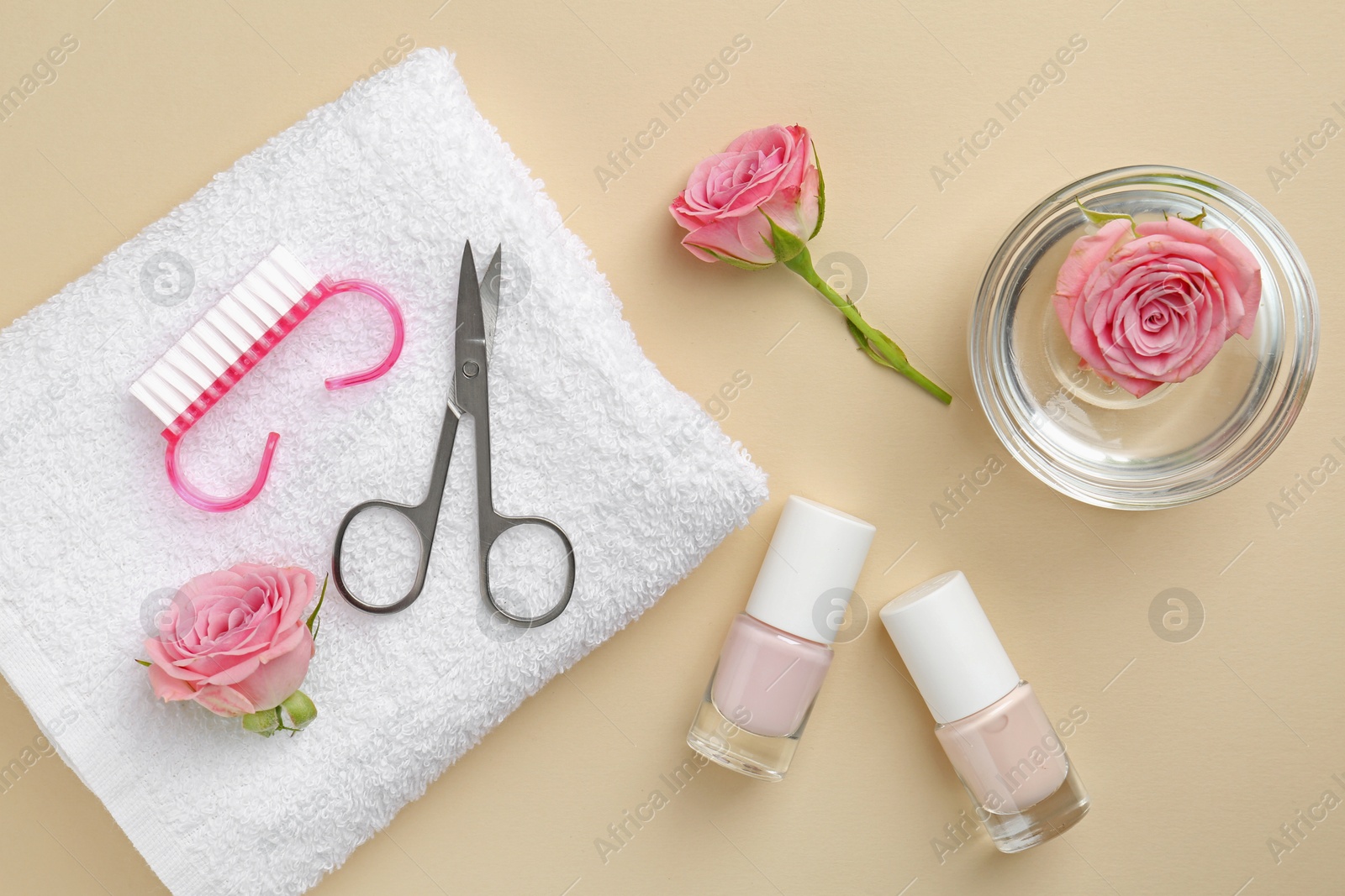 Photo of Set of pedicure tools and flowers on beige background, flat lay