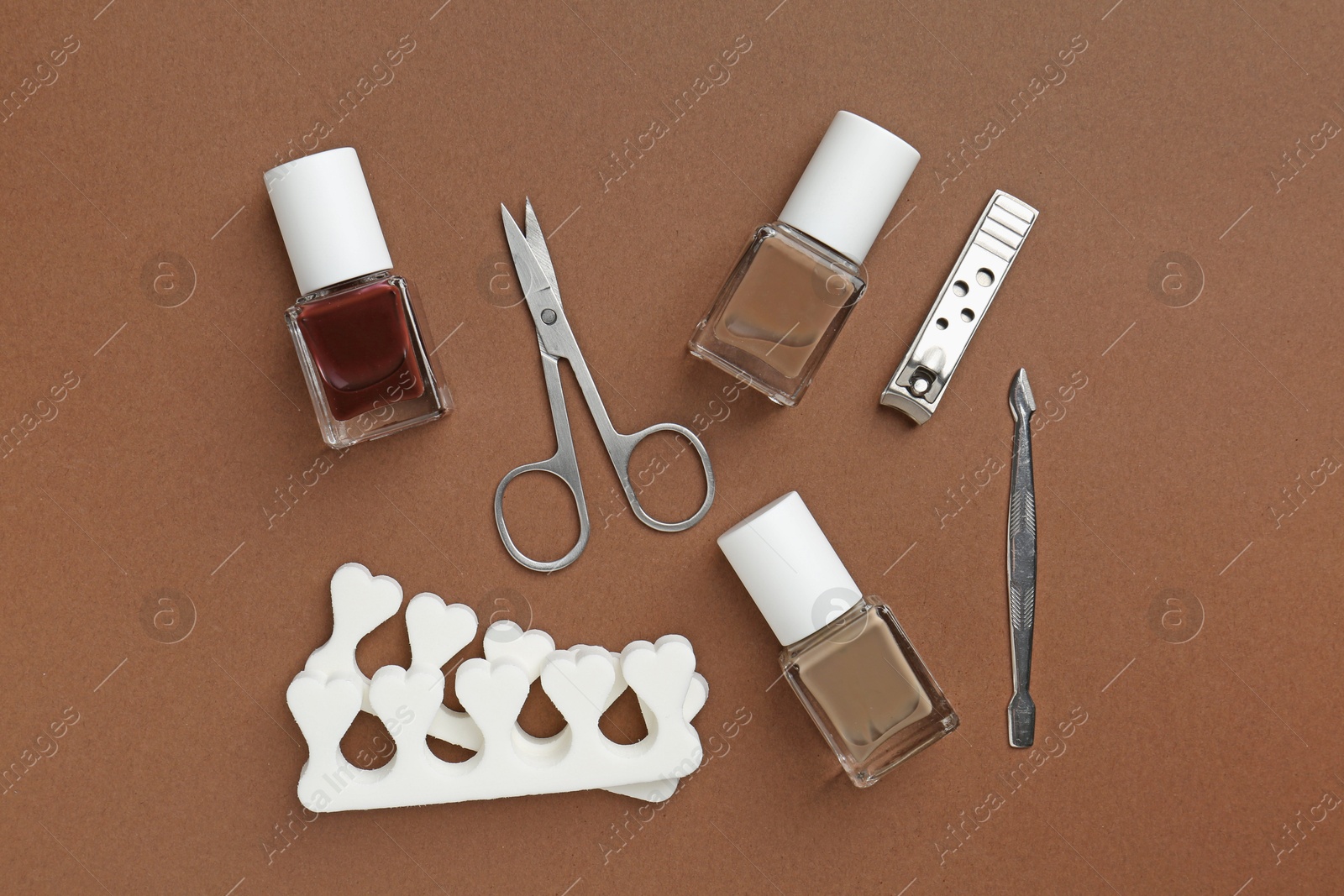 Photo of Set of pedicure tools on brown background, flat lay