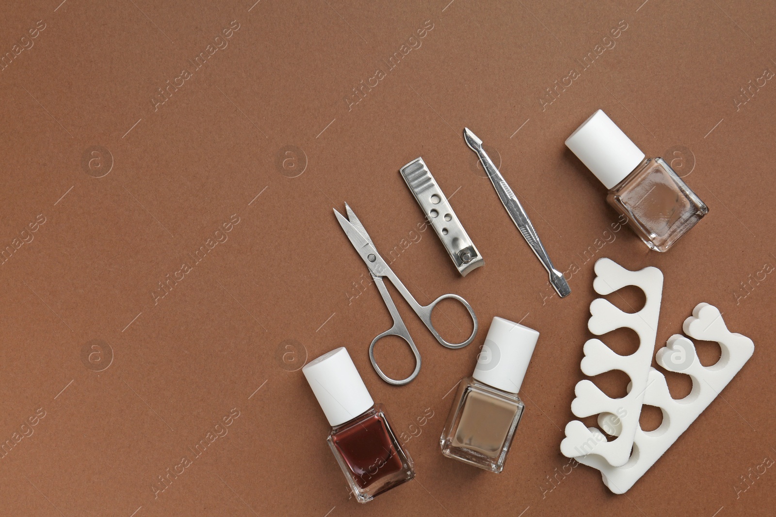 Photo of Set of pedicure tools on brown background, flat lay. Space for text