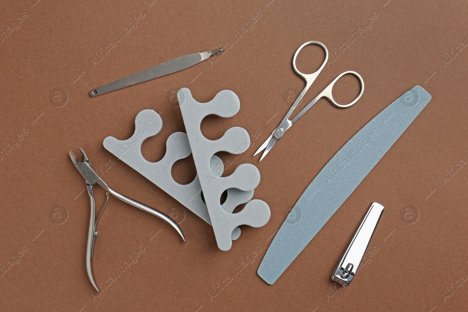 Photo of Set of pedicure tools on brown background, flat lay