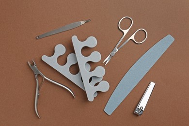 Photo of Set of pedicure tools on brown background, flat lay