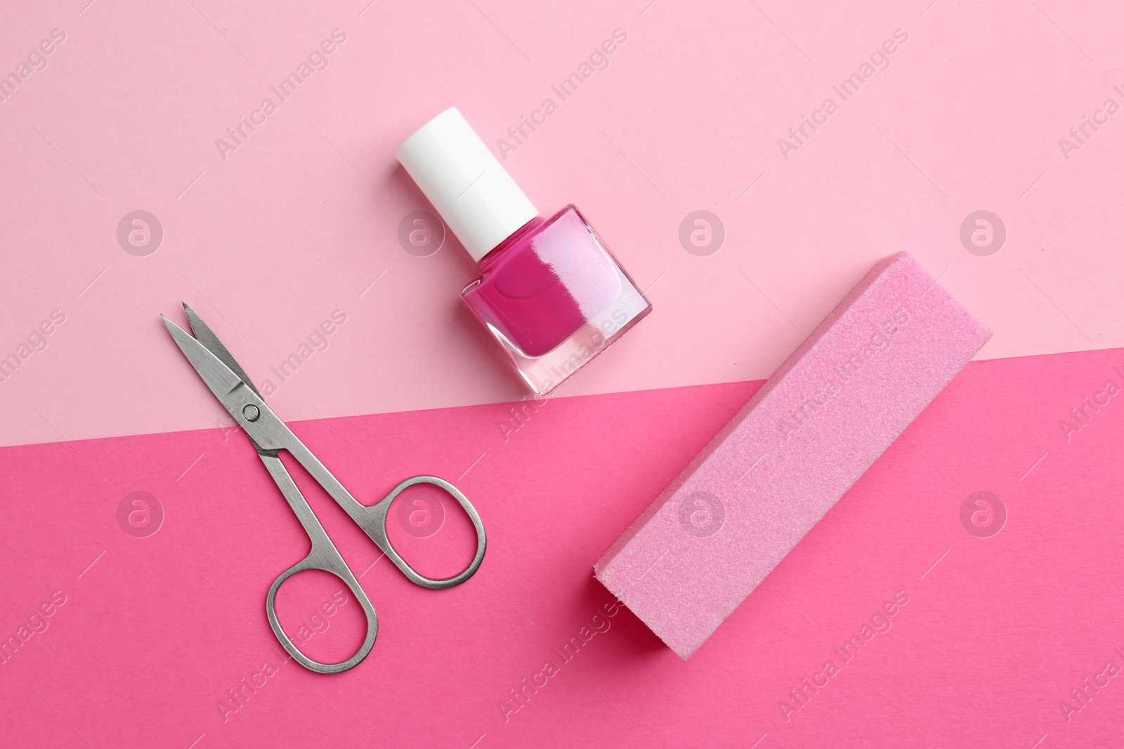 Photo of Pedicure procedure. Nail polish in bottle, buffer and scissors on pink background, flat lay