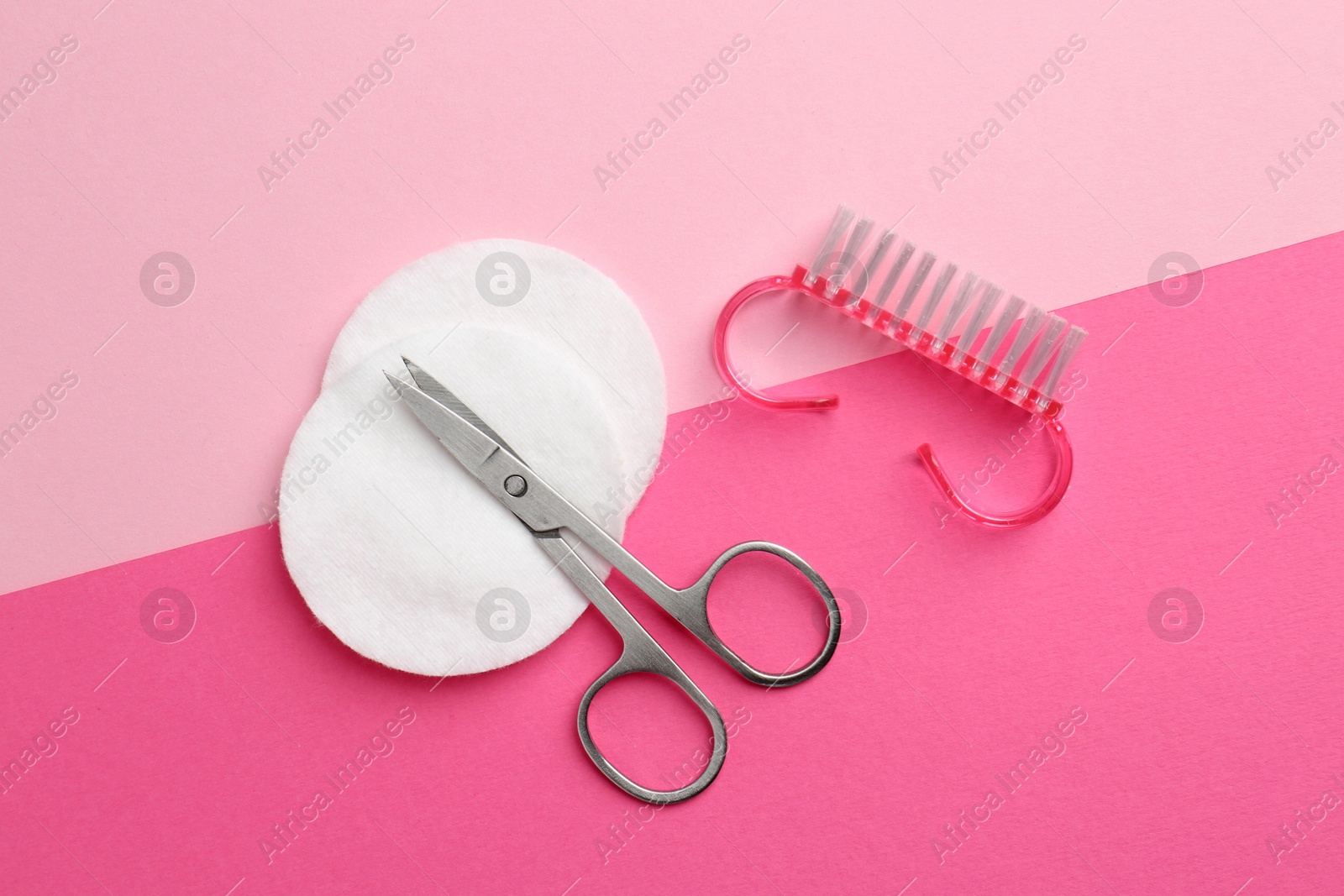 Photo of Pedicure procedure. Scissors, brush and cotton pads on pink background, flat lay